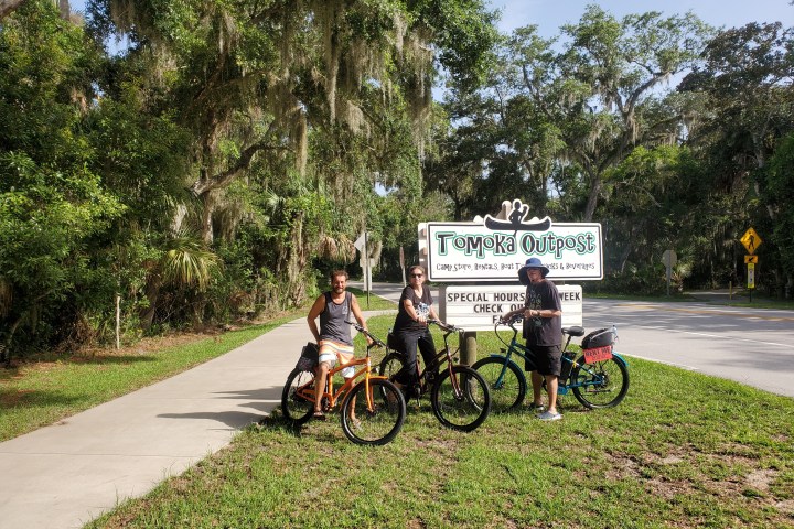people on ebikes in front of the Tomoka Outpost sign