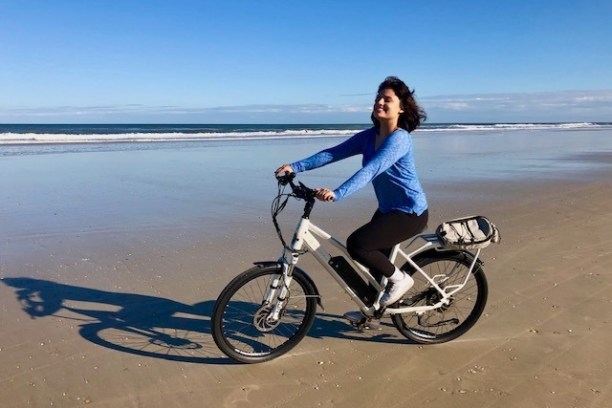 a woman riding a bike on the beach