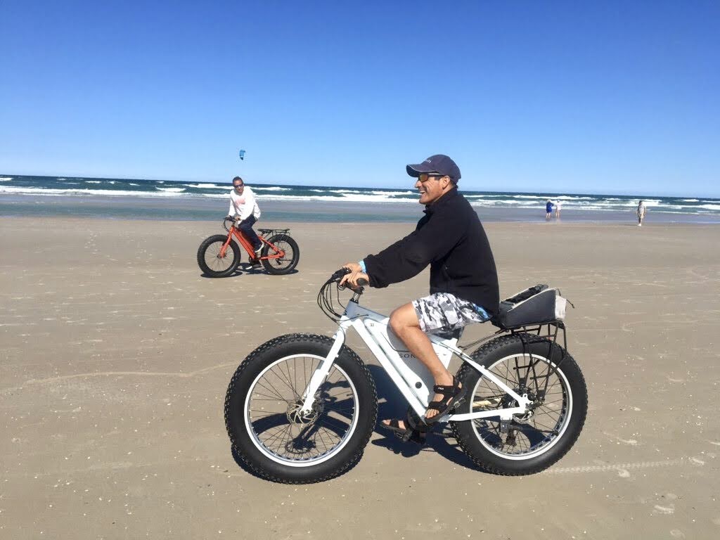 a man riding a bike down a beach